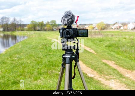 Digitalkamera mit Mikrofon auf einem Stativ Nahaufnahme. Spiegellose Aufnahme von Digitalkamera und Mikrofon während der Übertragung in der Natur. Stockfoto