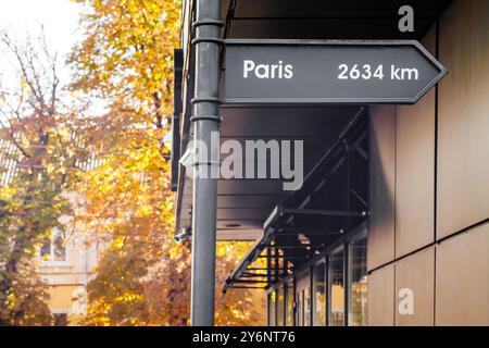 Ein dekoratives Straßenschild mit Wegbeschreibungen und Entfernungen zu den größten Städten der Welt in der Nähe des Cafés. Stockfoto