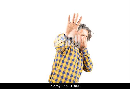 Bärtiger Mann in kariertem Hemd, der etwas riecht und ekelhaft seinen Atem mit Fingern in der Nase anhält Stockfoto
