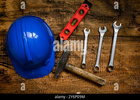 Klauenhammer, Schraubenschlüssel und Wasserwaage auf einer hölzernen Werkbank von oben. Stockfoto