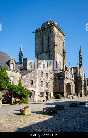 Blick auf die Kirche Saint Ronan vom Dorfplatz, alte Häuser und Touristen. Stockfoto