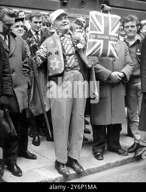 Budget Day in der Downing Street. London, und sind wir unruhig? Offensichtlich nicht, denn dieser unbekannte und überenthusiastische Brite zeigt eine Tragetasche von Union Jack, während er mit einer Menge von mehreren Hundert wartet, damit Mr. Roy Jenkins, der Finanzminister, die Downing Street 11 in das Unterhaus verlässt. Wo er heute Nachmittag (Dienstag) seine Rede zum Haushalt halten sollte. 19. März 1968 Stockfoto