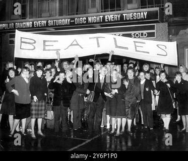 Teenager-Fans der Beatles trotzen dem heftigen Regen und ziehen am Dienstag mit einem Banner vor dem Adelphi Cinema, Bath Road, Slough, Buckinghamshire, wo heute Abend zu sehen ist. frisch von ihrem Erfolg bei der Royal Variety Performance von gestern Abend. Die Polizei in Slough hatte heute Pläne für "Operation Beatles" gemacht und zusätzliche Männer im Dienst, um Probleme mit der Menschenmenge zu lösen. - 5. November 1963 Stockfoto