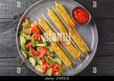 Vegane Kebab Sticks gebratene Aubergine serviert mit Gemüsesalat und Tomatensauce Close up auf Teller auf Holztisch. Horizontale Draufsicht von oben Stockfoto