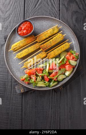 Panierte Auberginen-Sticks mit Mozzarella-Käse, serviert mit frischem Salat und Sauce in Nahaufnahme auf dem Teller auf dem Tisch. Vertikale Draufsicht von oben Stockfoto