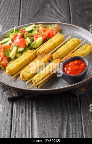 Panierte Auberginen-Sticks mit Mozzarella-Käse, serviert mit frischem Salat und Sauce in Nahaufnahme auf dem Teller auf dem Tisch. Vertikal Stockfoto