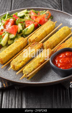 Gebratene Auberginen-Sticks alla milanese in Panierung serviert mit frischem Salat in Nahaufnahme auf einem Teller auf einem Tisch. Vertikal Stockfoto