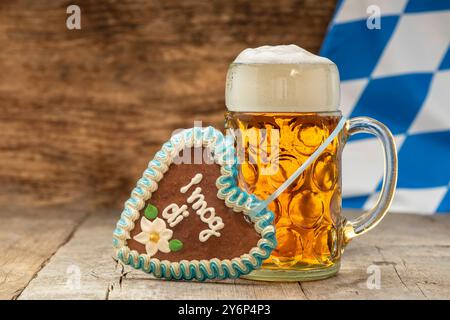 Oktoberfest in München ein Maßkrug Bier steht auf einem Holzbrett mit der weiß-blauen Bayernfahne im Hintergrund *** Oktoberfest in München Eine Tasse Be Stockfoto