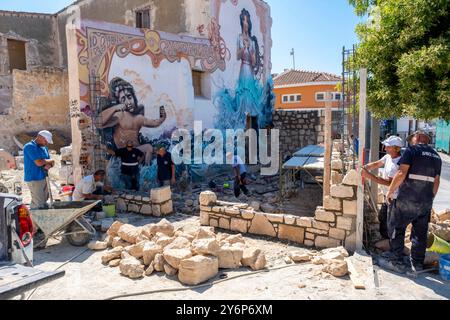 Arbeiter bauen eine Steinmauer neben einem farbenfrohen Wandgemälde in der Altstadt von Paphos, Paphos, Zypern. Stockfoto