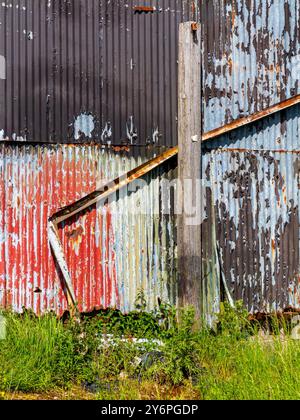 Detail einer gewellten Eisenwand auf einem Metallgebäude mit Anzeichen von Rost und Verfall. Stockfoto