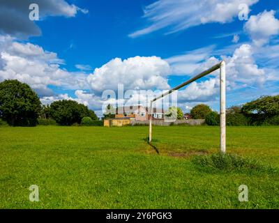 Torpfosten auf einem Fußball- oder Fußballfeld in einem Vorstadtpark mit Häusern dahinter und blauem Himmel mit weißen Wolken darüber. Stockfoto