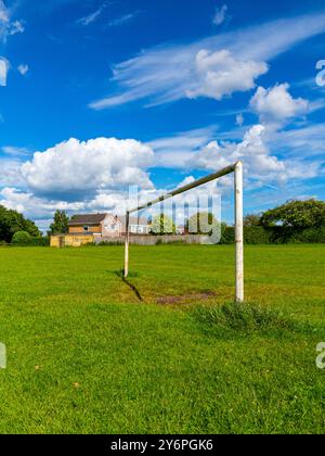 Torpfosten auf einem Fußball- oder Fußballfeld in einem Vorstadtpark mit Häusern dahinter und blauem Himmel mit weißen Wolken darüber. Stockfoto