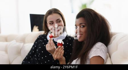 Lächelnde Mädchen essen leckere frische Erdbeere mit Schlagsahne bedeckt Stockfoto