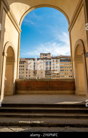 Ein malerischer Blick auf Wohngebäude durch einen historischen Bogengang in der Nähe der Brücke Ponte Vecchio in Florenz, Italien. Das Sonnenlicht verstärkt t Stockfoto