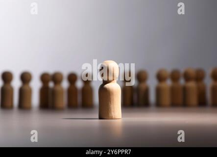 Einsamkeitskonzept. Menschliche Figur, die von anderen fern ist, auf grauem Hintergrund Stockfoto