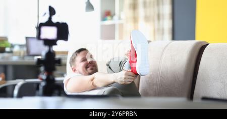 Männer mittleren Alters setzen sich trendige rote Sneaker an und zeigen sie vor der Kamera Stockfoto