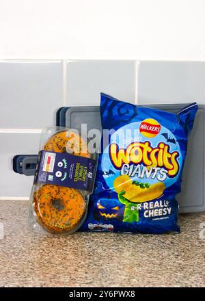 London, England, 26. September 2024: Halloween-Branding-Essen, Beutel mit Crisps und Donuts in der Küche Stockfoto