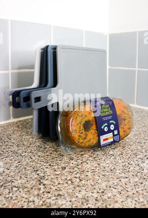 London, England, 26. September 2024: 4er-Pack Co-Cop Donuts für Halloween, mit Orangenglasur, Ballen, gelben und grünen Streuseln in der Küche Stockfoto