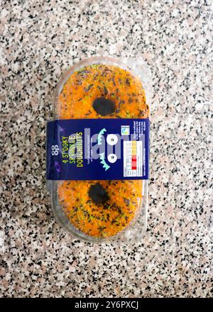 London, England, 26. September 2024: 4er-Pack Co-Cop Donuts für Halloween, mit Orangenglasur, schwarzen, gelben und grünen Streuseln in der Küche Stockfoto