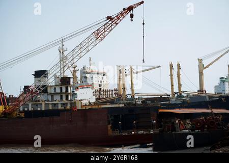 Ein großes Schiff wird derzeit von einem Kran in der Werft Alang angehoben, was das industrielle Verfahren des maritimen Recyclings im dezember veranschaulicht Stockfoto