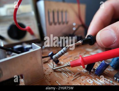 Techniker, der elektronische Bauteile auf der Leiterplatte prüft und misst. Fokus auf Widerstand. Stockfoto