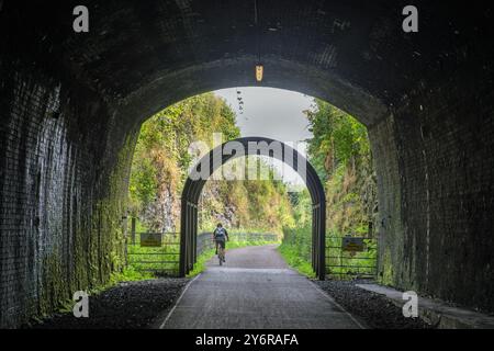 Ein Radfahrer, der den Grabstein Tunnel am Monsal Head Viaduct verlässt, Monsal Dale, Peak District, Derbyshire, England Stockfoto