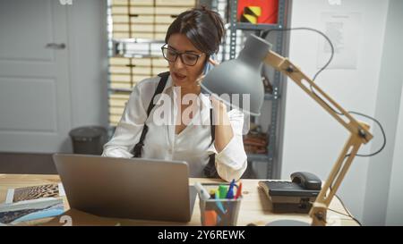 Eine reife Frau ermittelt in einem Polizeibüro und analysiert Beweise neben Computer und Telefon. Stockfoto