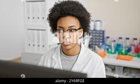 Fokussierte afroamerikanische Wissenschaftlerin, die in einem Labor arbeitet, umgeben von Geräten. Stockfoto