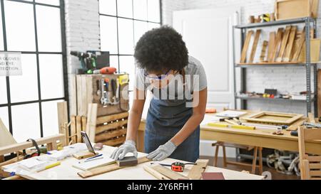 Eine schwarze Frau versändet in einer hellen Tischlerei sorgfältig Holz und symbolisiert Handwerkskunst und Handarbeit. Stockfoto