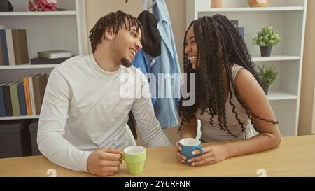 Ein fröhlicher Mann und eine fröhliche Frau genießen einen liebevollen Moment zusammen, halten Tassen in einem gemütlichen Wohnzimmer. Stockfoto