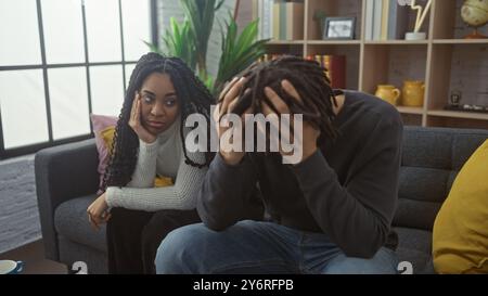 Ein besorgter Mann und eine besorgte Frau sitzen zusammen in einem modernen Wohnzimmer und zeigen familiäre Probleme. Stockfoto
