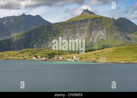 Kleine Stadt in der Nähe des Sees vom gegenüberliegenden Ufer und felsigen Bergen im Hintergrund, Lofoten Norwegen Stockfoto