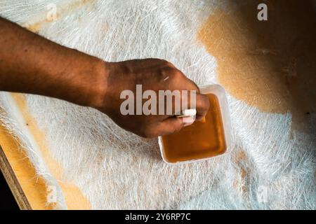 Tauchen Sie den Pinsel in die Glasfaserlösung in einen Behälter auf der Glasfaserplatte. Stockfoto
