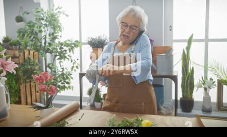 Eine ältere Frau mit Brille zieht Handschuhe in einem Blumenladen an, mit verschiedenen Pflanzen um sie herum. Stockfoto