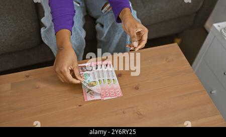 Eine Frau zählt neuseeland-Dollar auf einem Tisch drinnen und betont dabei Finanzen, Währung und Wirtschaft in einer inländischen Umgebung. Stockfoto