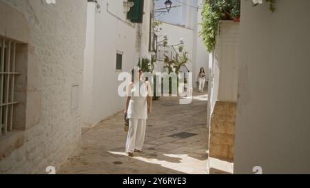 Eine junge hispanische Frau schlendert durch die bezaubernden alten Straßen von locorotondo, apulien, italien, und schätzt die wunderschöne weiße Architektur und Stockfoto