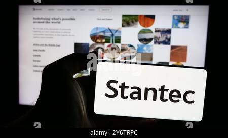 In dieser Abbildung hält eine Person ein Smartphone mit dem Logo des kanadischen Professional Services Unternehmens Stantec Inc. Vor der Website. Stockfoto