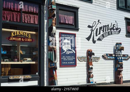 Skagway, AK, USA - 25. Juni 2024: Drei Totempfähle stehen draußen, um einen Schmuck- und Souvenirladen in Skagway zu besuchen. Stockfoto