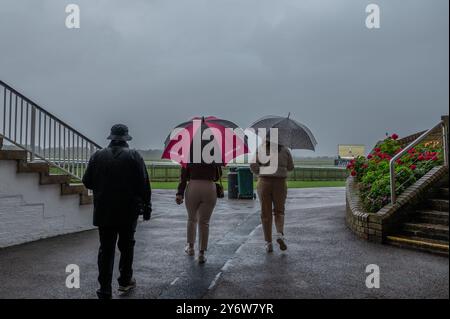 Newmarket, Großbritannien. September 2024. Blick auf die Menschen, die am ersten Tag des Cambridgeshire Meetings mit Regenschirmen auf der Newmarket Racecourse laufen. Das Cambridgeshire Meeting findet an drei Tagen auf den Newmarket Racecourses statt und ist eines der wichtigsten Veranstaltungen der Herbstsaison. (Foto: David Tramontan/SOPA Images/SIPA USA) Credit: SIPA USA/Alamy Live News Stockfoto