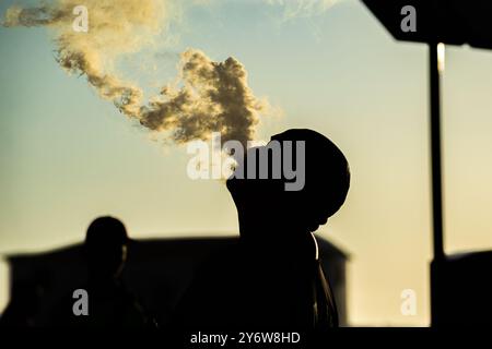 Salvador, Bahia, Brasilien - 21. Dezember 2019: Ein nicht identifizierter Mann in Silhouette wird gesehen, wie er draußen eine Rauchwolke dampft und ausatmet. Salvador, Bahia. Stockfoto