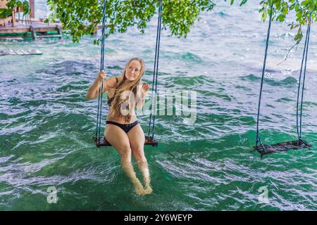 Wunderschöne weibliche Touristen, die sich während einer Kajakfahrt auf einer Schaukel in Laguna Bacalar in Mexiko entspannen. Weibliche Touristen schwingen über den Lake Bacalar mit Füßen im Stockfoto