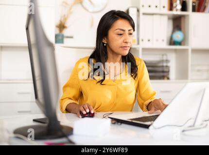 Konzentrierte hispanische Geschäftsfrau, die im Büro mit Computer arbeitet Stockfoto