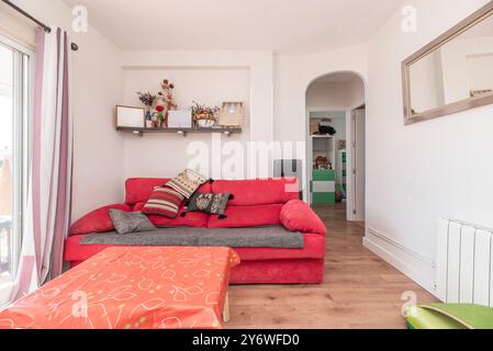 Wohnzimmer mit Zugang zur Terrasse, rotem Zweisitzer-Sofa und Bogenzugang Stockfoto