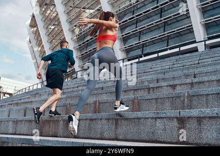 Rückansicht eines jungen Mannes und einer Frau in Sportbekleidung beim Joggen auf der Treppe im Freien Stockfoto