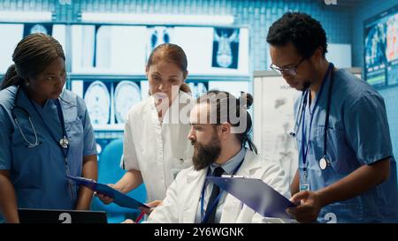 Medizinisches Team diskutiert Röntgenergebnisse und Patientenversorgungsstrategie in einem Behandlungszentrum, Expertise in Radiologie und Krankheitsprävention. Zusammenarbeit sichert Diagnose und Medizin. Kamera A.. Stockfoto