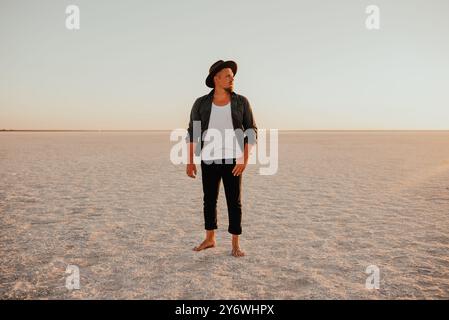 Porträt eines jungen gebräunten blonden europäischen mutigen Mannes mit Barfuß, Boho-Hut-Stil. Ukrainische Landschaft Sonnenuntergang, berühmte Orte der Ukraine rosa Stockfoto