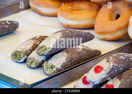 Hausgemachtes süßes Gebäck Cannolo siciiano gefüllt mit Mandel, Pistazien, Zitronen, Vanille und Schokoladencreme auf dem Lebensmittelmarkt in Italien Stockfoto