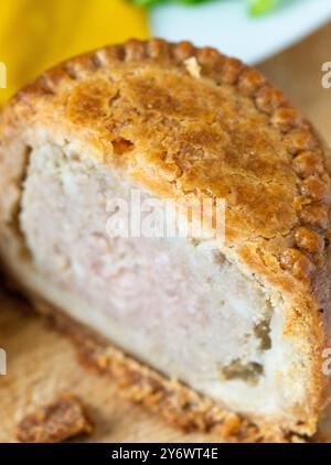 Abstrakter Blick auf einen leckeren traditionellen britischen Snack zur Mittagszeit in mittlerer Zubereitung, auf einem hölzernen Schneidebrett, mit süßer Gurke, Senf und Tomaten als A Stockfoto