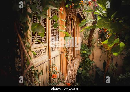 Ruhiges traditionelles marokkanisches Riad Courtyard in Marrakesch mit üppigem Grün, sonnendurchfluteten Holztüren und traditionellen architektonischen Details, Einem ruhigen Esc Stockfoto