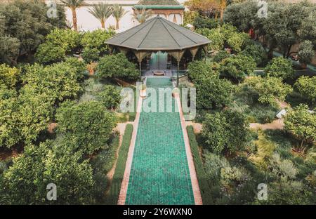 Üppiger Gartenweg mit grünen Fliesen und grünen Pflanzen im Le Jardin Secret Marrakech, symmetrisches marokkanisches Design, ruhige, luxuriöse, elegante Outdoor-Umgebung Stockfoto